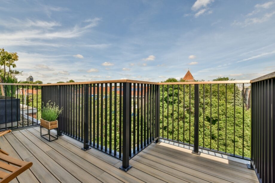 Taras z kompozytu z widokiem na zielone drzewa i dachy budynków.